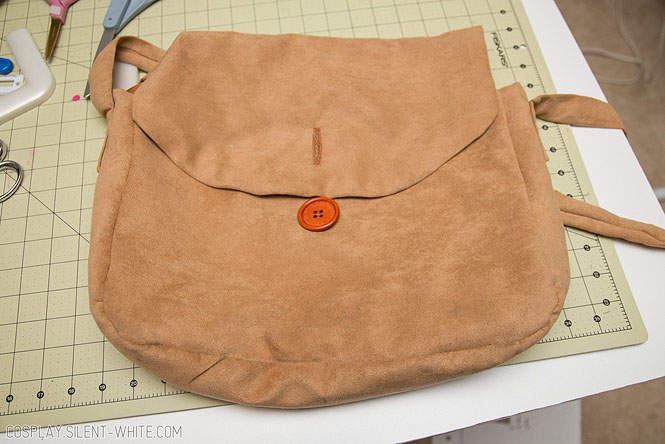 Hand holding a brown suede bag open to show the inside