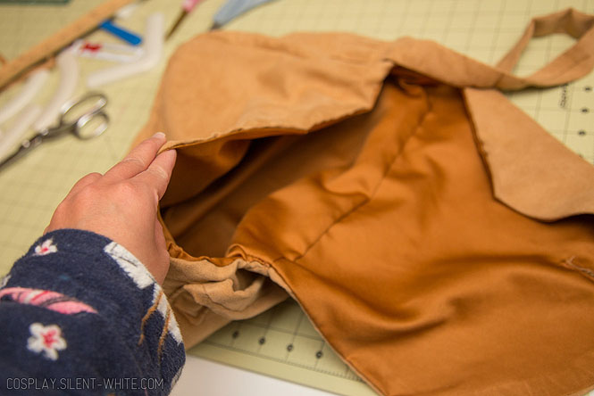 Hand holding a brown suede bag open to show the inside