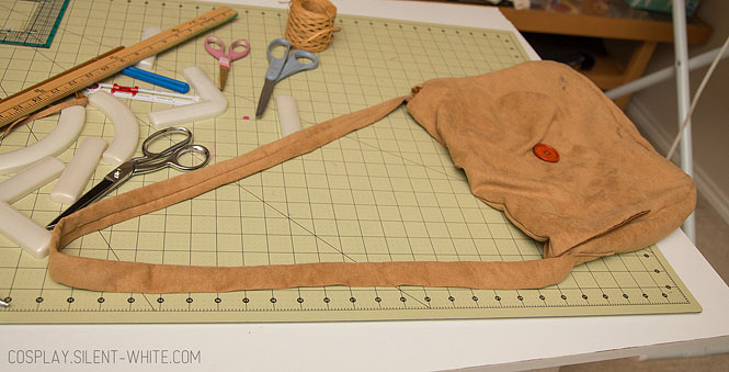 Brown suede bag laying on a table with strap laid out