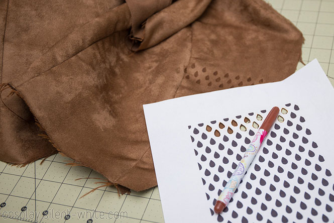 In progress photo of applying a pattern using a brown fabric marker and paper stencil